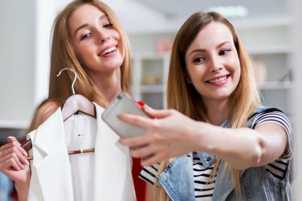 mulheres da geração millennials usando smartphone dentro da loja