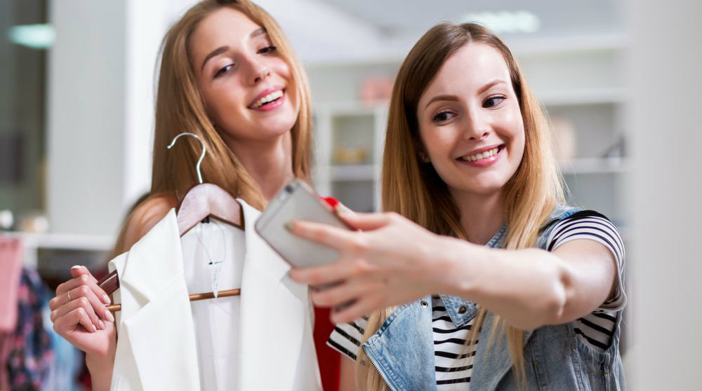 mulheres da geração millennials usando smartphone dentro da loja