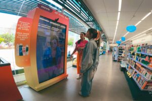 Consumidora utilizando tecnologia no ponto de venda com tela interativa em ambiente de varejo físico