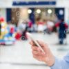 Consumidor utilizando smartphone em ambiente de varejo conectado com ícones digitais representando tecnologia e jornada do consumidor no varejo físico.