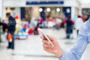 Consumidor utilizando smartphone em ambiente de varejo conectado com ícones digitais representando tecnologia e jornada do consumidor no varejo físico.