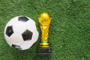 FIFA World Cup in retail concept featuring a soccer ball and championship trophy on a grass field, representing experiential marketing and consumer engagement opportunities.