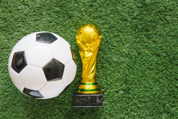 FIFA World Cup in retail concept featuring a soccer ball and championship trophy on a grass field, representing experiential marketing and consumer engagement opportunities.